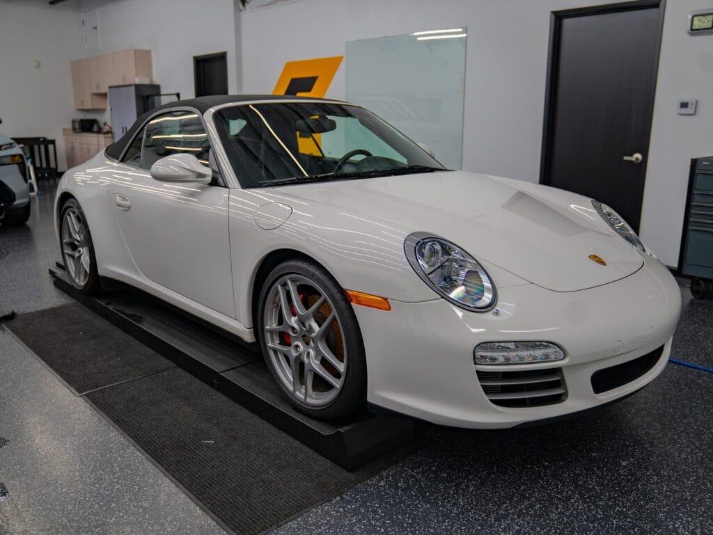 White convertible sports car in a workshop setting.